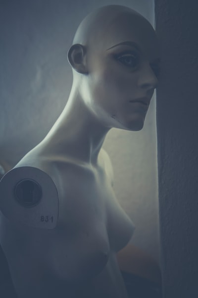 一个无臂的人体模型的头靠着一堵墙。
